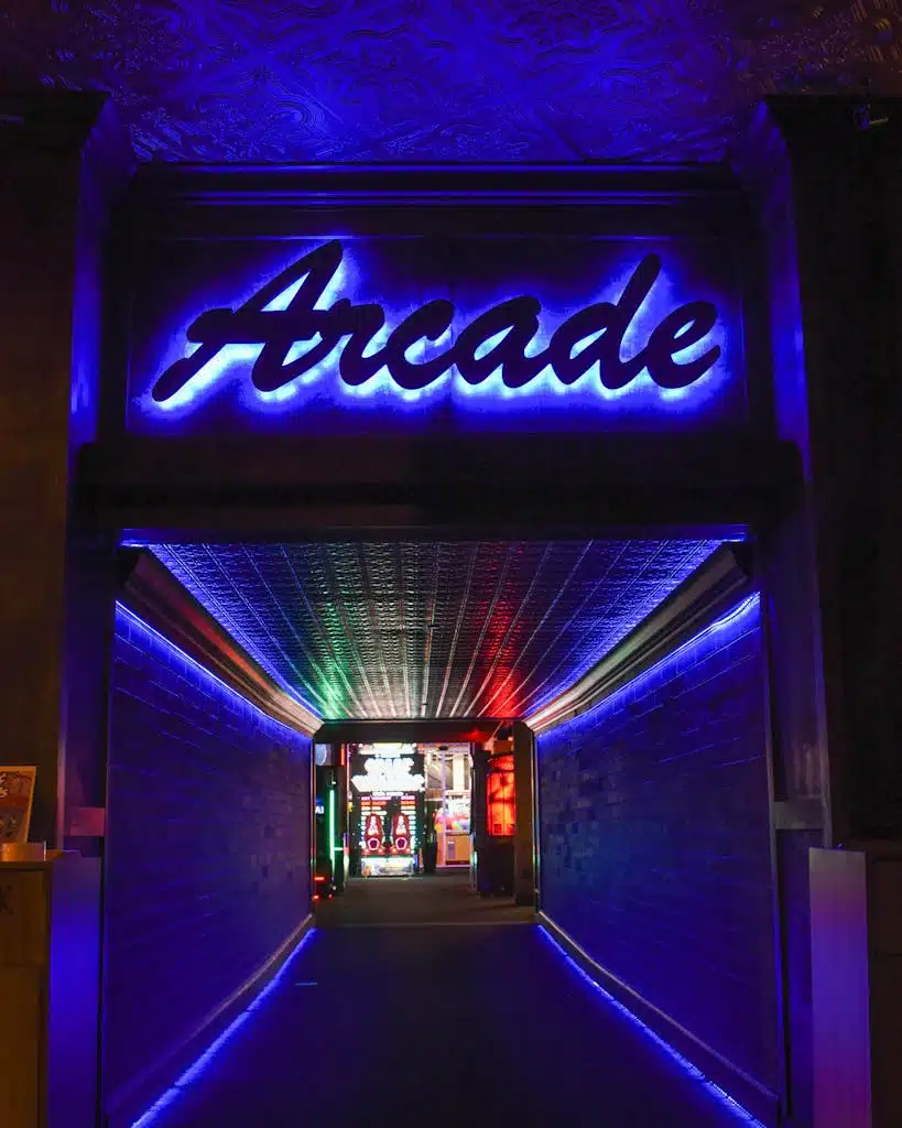 Vibrant neon light hallway leading to retro arcade gameplay area.